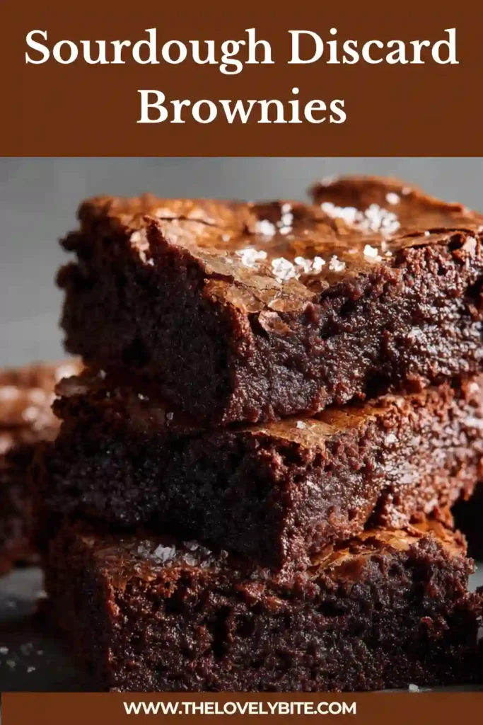 Freshly baked sourdough discard brownies cut into squares, displaying dense texture and rich cocoa color on a parchment-lined tray.