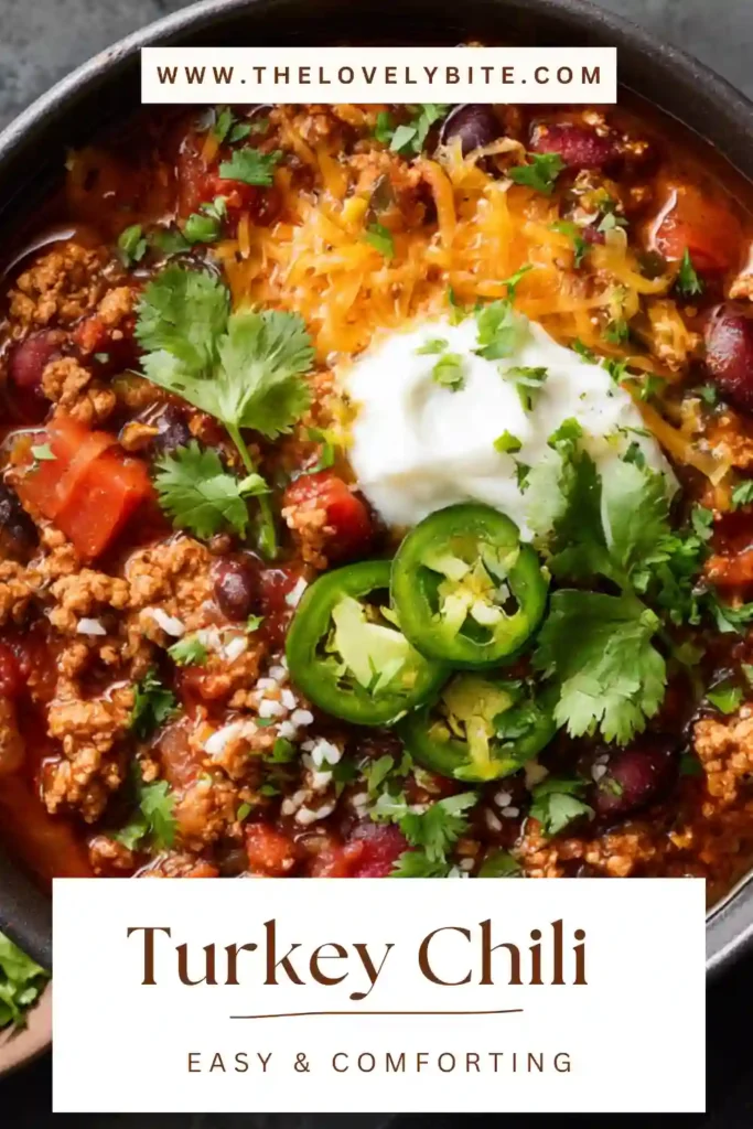 This Easy Turkey Chili is served warm in a bowl with chopped cilantro and shredded Cheddar on top. The healthy turkey chili has a rich red color and a chunky, satisfying texture.