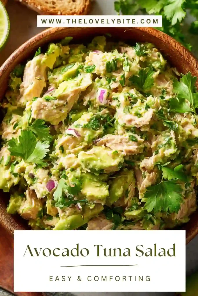 Fresh avocado tuna salad served in a bowl with lime wedges and chopped vegetables. This dish highlights a creamy, low carb meal option.