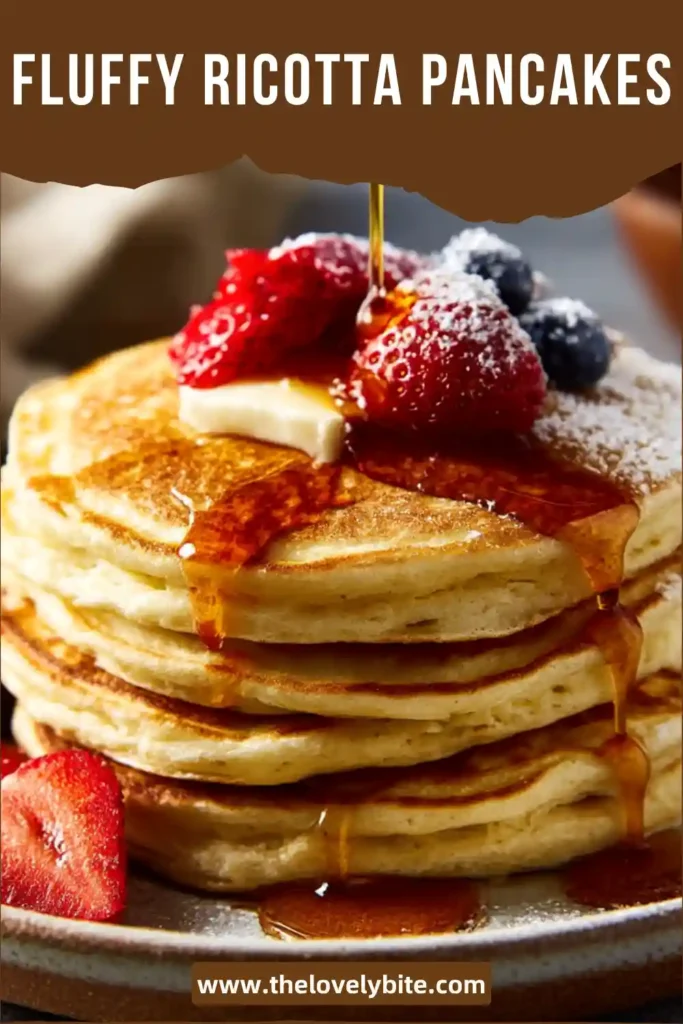 Fluffy ricotta pancakes stacked with fresh strawberries and maple syrup on top. The pancakes look soft, golden, and airy.