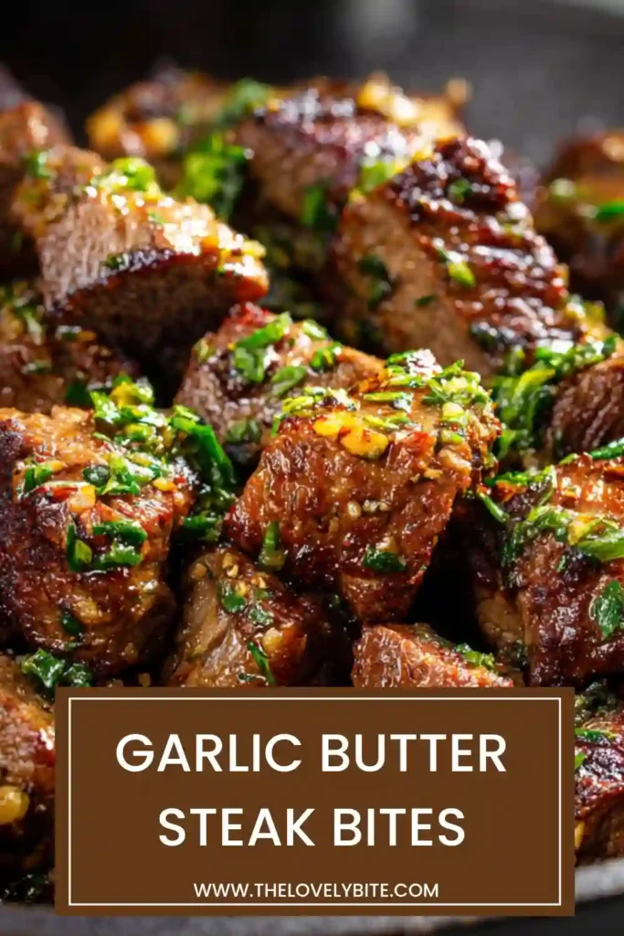 Close-up of garlic butter steak bites with golden crust and visible garlic and herbs in a pan.