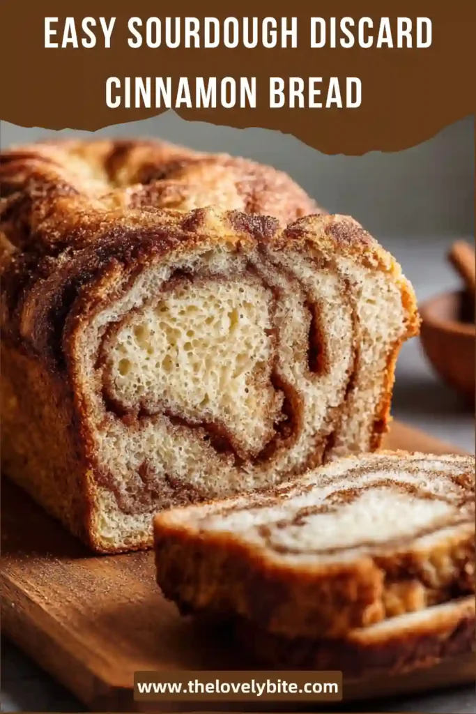 Freshly baked Sourdough Discard Cinnamon Bread in a loaf pan with a golden top and marbled cinnamon sugar layers. The bread has a rich homemade look that highlights its soft texture and cozy flavor.