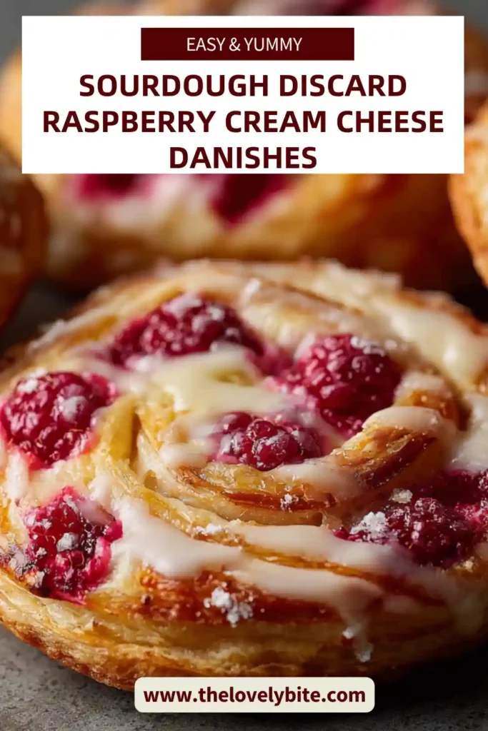 Homemade sourdough discard raspberry cream cheese danishes arranged on a tray with a light glaze drizzle. The golden crust contrasts with vibrant raspberry filling.