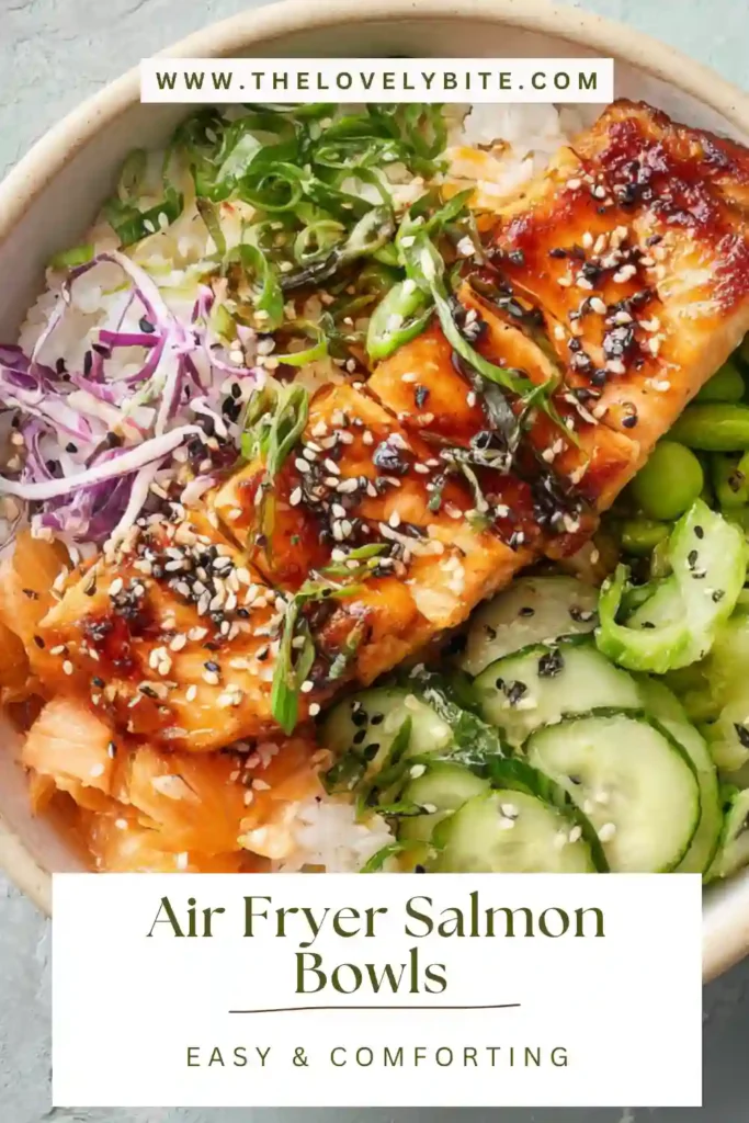 A bowl of air fryer salmon served over rice with avocado, cucumber, and edamame, drizzled with sauce. This Air Fryer Salmon Bowls recipe looks fresh and vibrant.