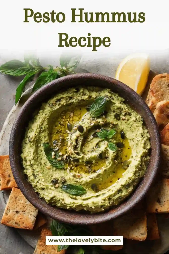 Close-up of rich and creamy Pesto Hummus garnished with black pepper and basil. This easy hummus recipe is made with chickpeas, tahini, lemon juice, and pesto.