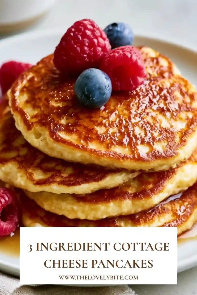 Golden brown cottage cheese pancakes stacked on a white plate with blueberries and strawberries.