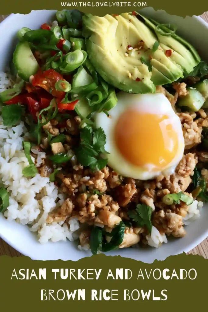 Close-up of an Asian-inspired turkey rice bowl filled with brown rice, zucchini, avocado slices, and a soft poached egg. Garnished with sesame seeds and green onions.