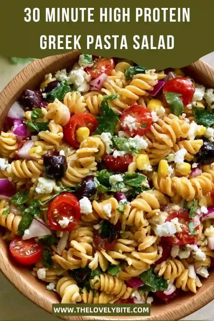 Mediterranean-style High Protein Greek Pasta Salad with feta crumbles, cucumber slices, tomatoes, and bell peppers. A healthy and colorful dish served chilled.