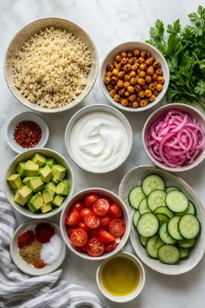 A wholesome vegetarian grain bowl featuring fluffy quinoa, roasted chickpeas, cherry tomatoes, cucumber slices, avocado, and garlic yogurt sauce.