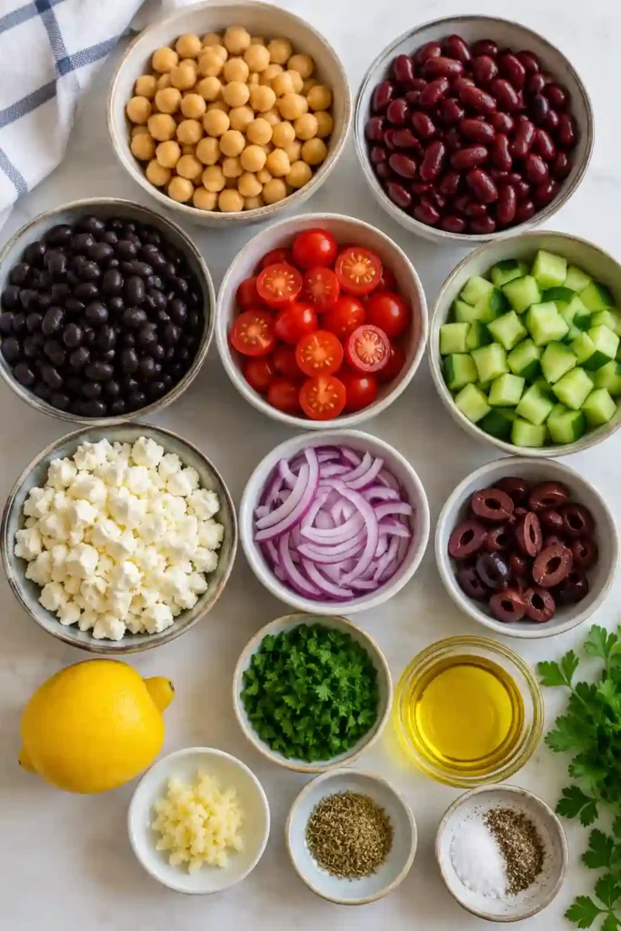 A colorful bowl of Mediterranean Dense Bean Salad made with chickpeas, kidney beans, black beans, fresh cucumber, cherry tomatoes, Kalamata olives, feta cheese, and parsley. This healthy Mediterranean salad is vibrant, protein-rich, and perfect for meal prep.