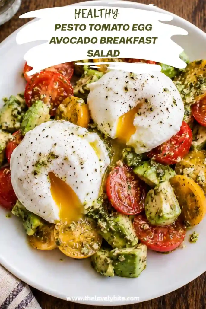 Fresh breakfast salad featuring ripe avocado, sliced cherry tomatoes, Parmesan flakes, basil pesto dressing, and soft poached eggs served on a white plate.