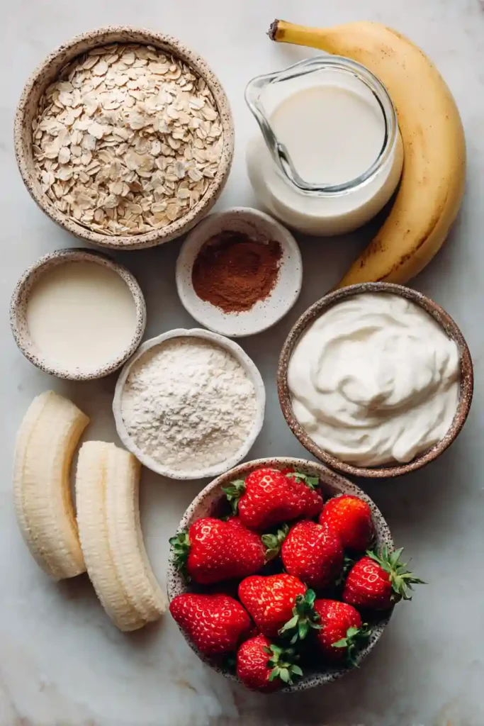A stack of Strawberry Banana Protein Pancakes topped with creamy vanilla yogurt and fresh chopped strawberries. These healthy high-protein pancakes are perfect for a nutritious breakfast.