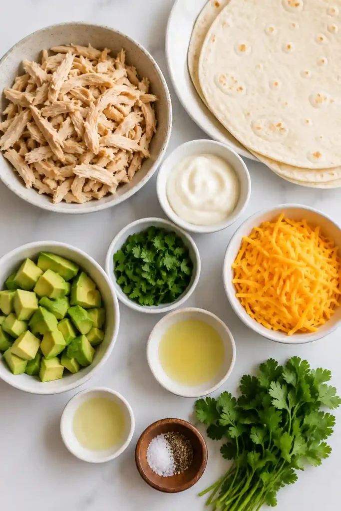 Homemade Crispy Chicken Avocado Wraps stacked on a serving platter with fresh avocado slices and cilantro garnish. A colorful and satisfying meal.