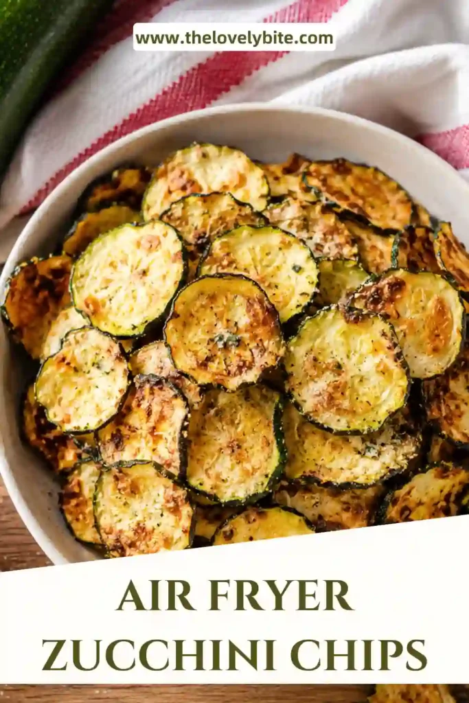A bowl of crispy Air Fryer Zucchini Chips seasoned with garlic powder and served with a creamy dipping sauce. The chips are golden brown and lightly crisped.