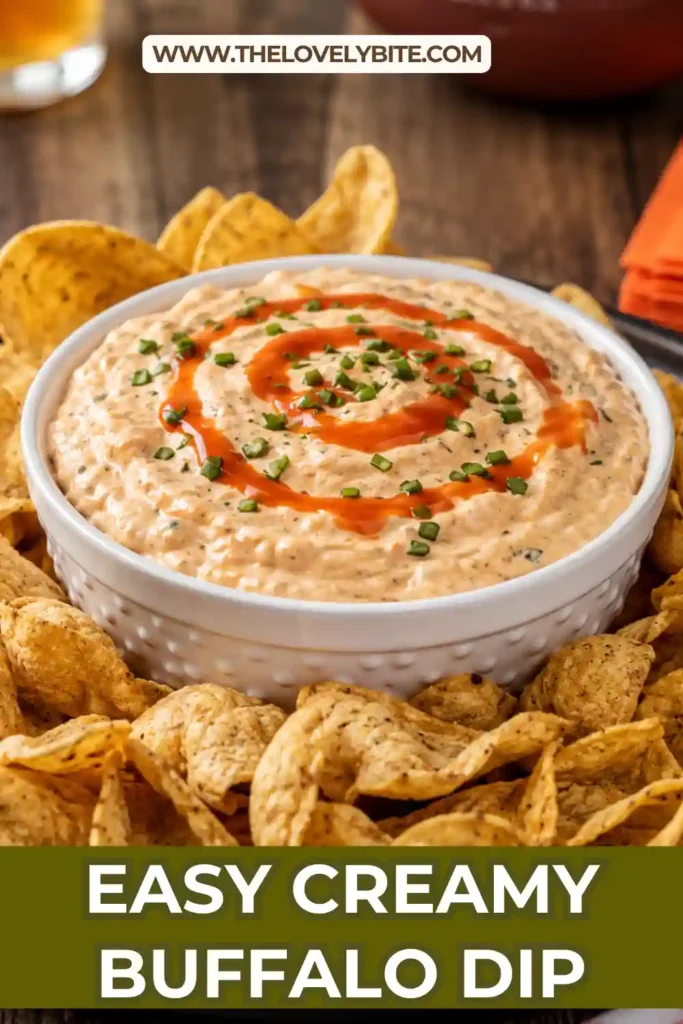 1. A bowl of Creamy Buffalo Dip topped with chopped chives and served with tortilla chips, celery, carrots, and pita bread in natural lighting.