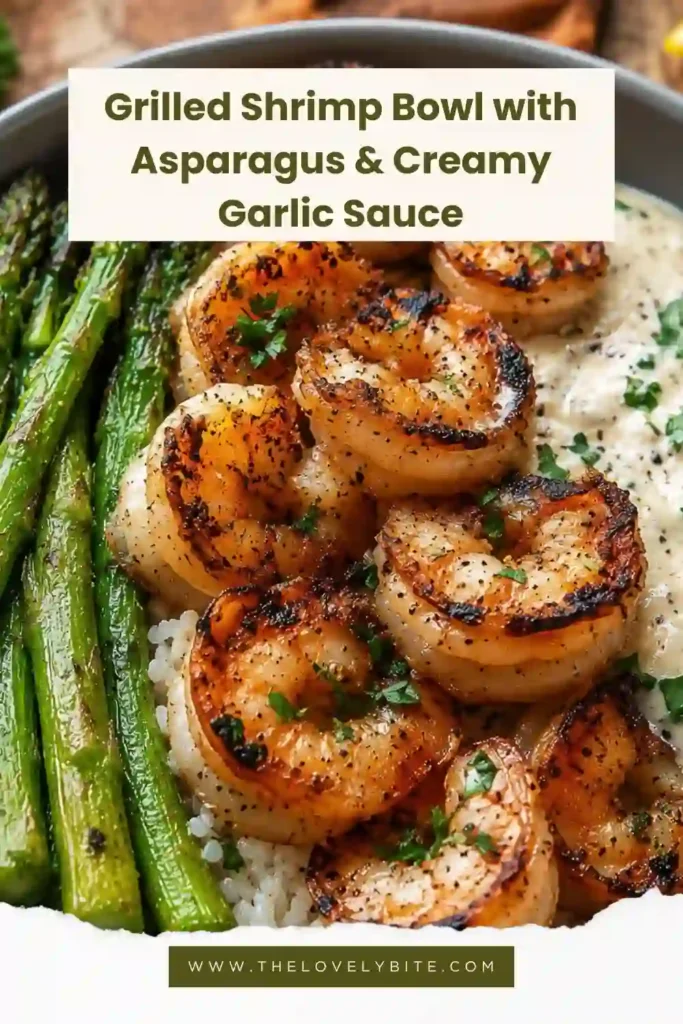 A grilled shrimp bowl with fluffy jasmine rice, charred asparagus, and creamy garlic Parmesan sauce topped with fresh parsley and lemon wedges. The shrimp are lightly seasoned and perfectly grilled.