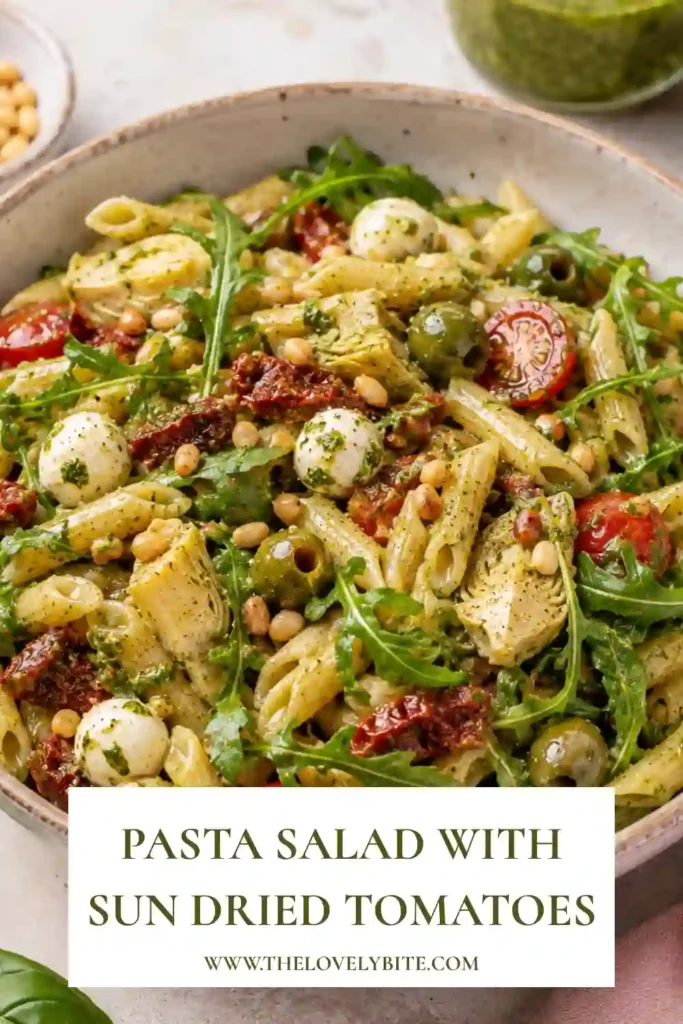 Fresh pasta salad tossed with homemade arugula pesto, mozzarella, olives, and colorful Mediterranean vegetables. A vibrant summer side dish.