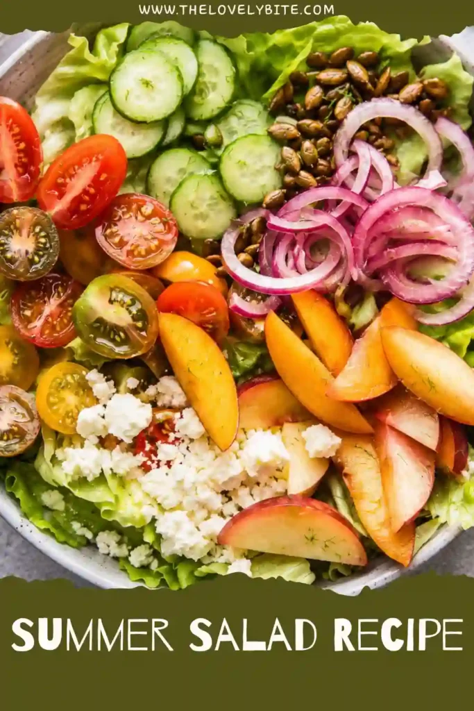 A healthy summer salad featuring sliced peaches, butter lettuce, cherry tomatoes, cucumbers, feta cheese, and roasted pepitas served with a fresh lime cilantro dressing.
