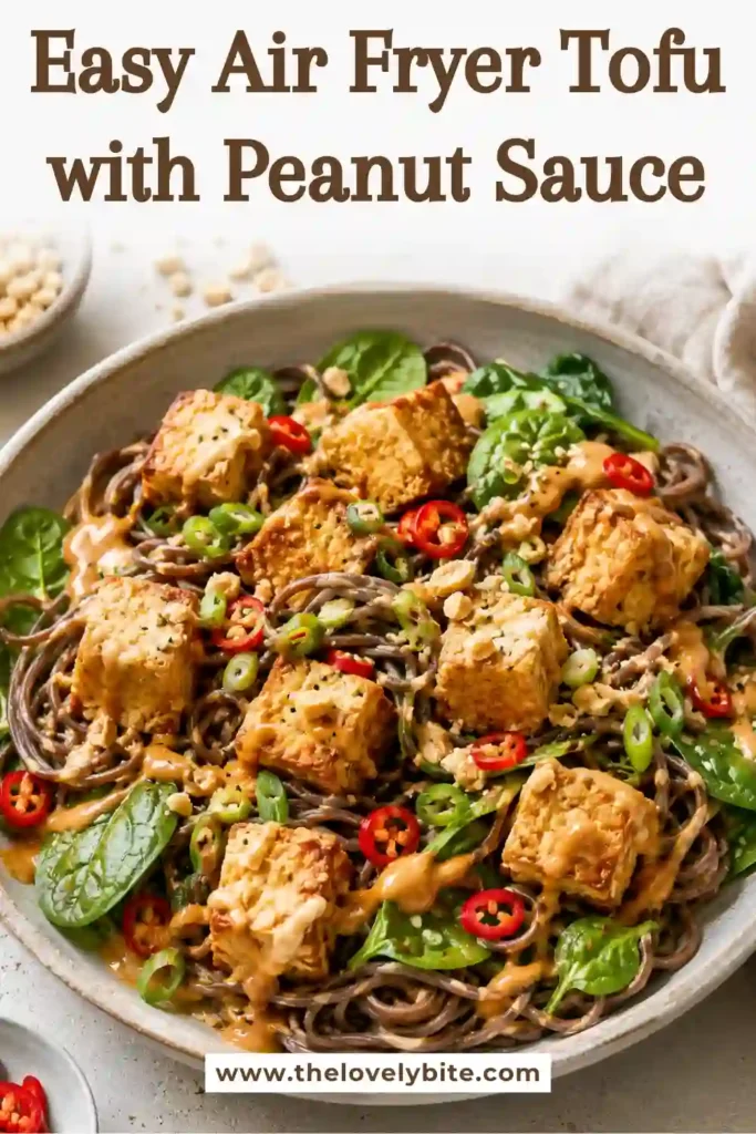 A bowl of crispy Air Fryer Tofu with Peanut Sauce served over soba noodles and fresh baby spinach. The golden tofu is coated in creamy peanut sauce for a healthy vegetarian dinner.