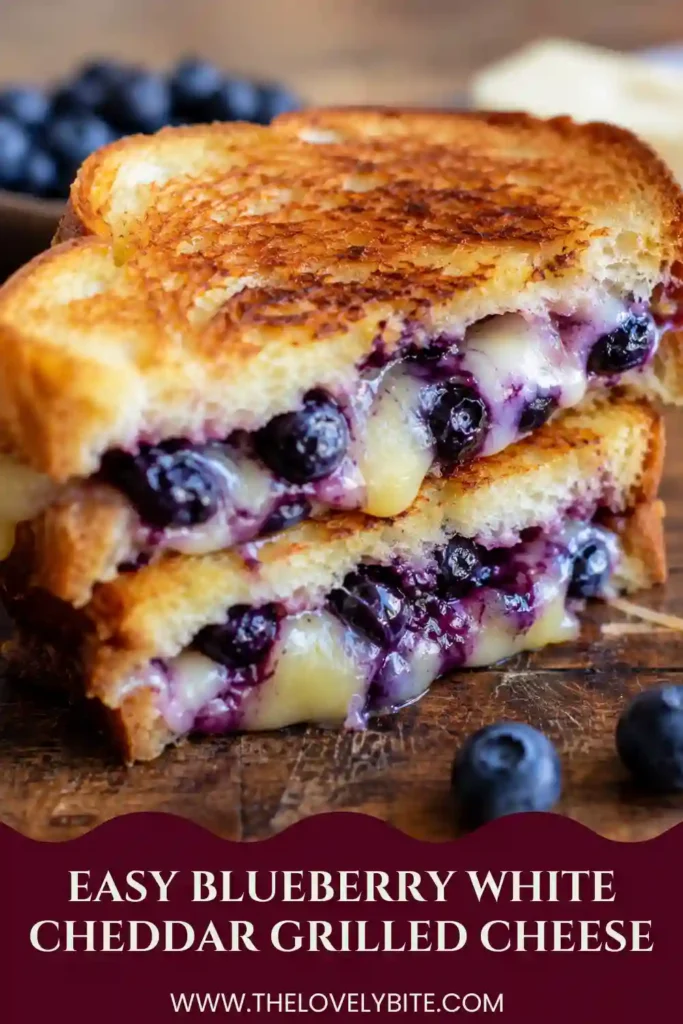 Blueberry white cheddar grilled cheese sliced in half to show melted mozzarella, sharp white cheddar, and homemade blueberry filling. The toasted sourdough is golden, crisp, and lightly sprinkled with flaky sea salt.