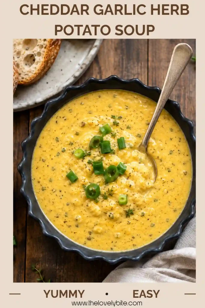 Homemade Cheddar Garlic Herb Potato Soup topped with chopped green onions and fresh herbs. The creamy cheddar potato soup is served warm with rustic bread for dipping.