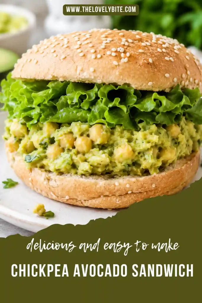 A homemade smashed chickpea sandwich served on whole grain bread with lettuce and a creamy chickpea avocado filling. Fresh herbs and chopped dill pickles are visible throughout the filling.