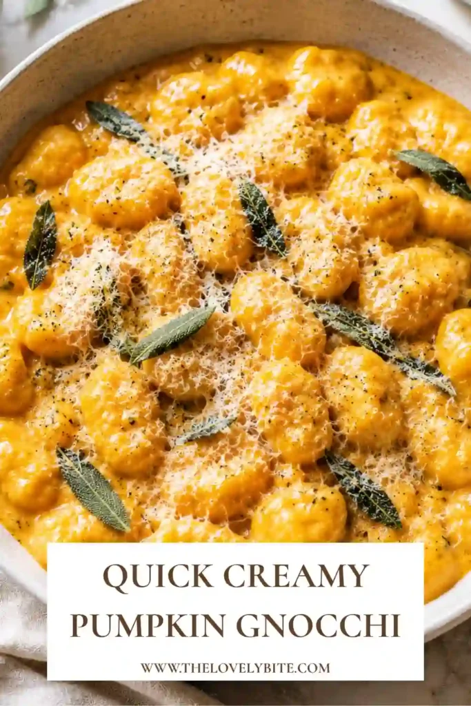 Close-up of pumpkin gnocchi covered in a creamy orange sauce and topped with grated Parmesan and chopped sage. The dish has a warm, comforting homemade appearance.