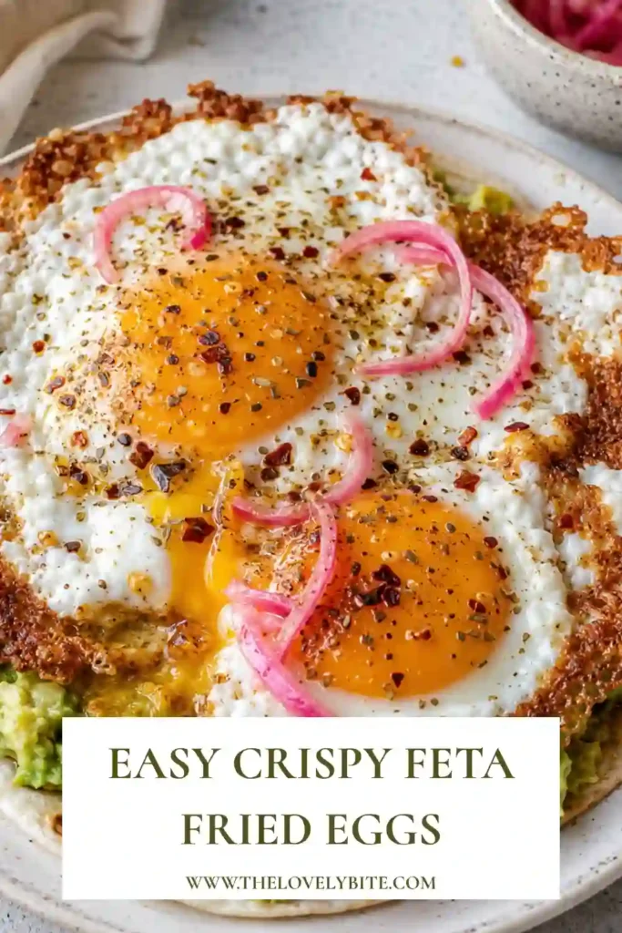 Crispy Feta Fried Eggs served over a warm tortilla with smashed avocado. Golden feta edges surround the fried egg with pickled onions, oregano and chili oil on top.