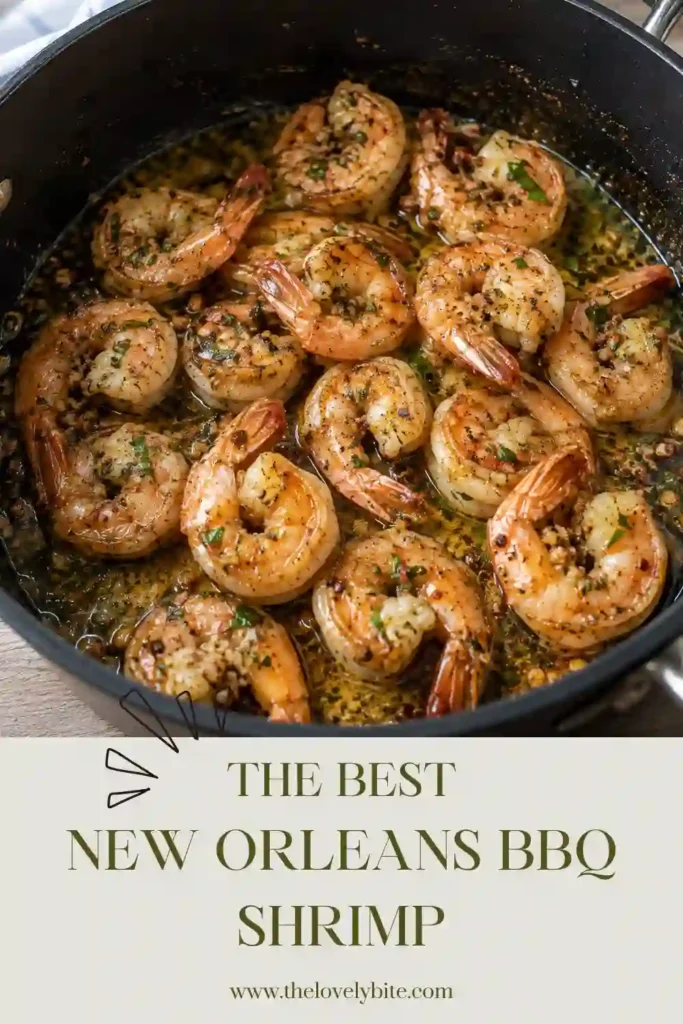 A close-up of New Orleans BBQ Shrimp covered in a spicy Cajun butter sauce with fresh lemon and herbs. The shrimp are served with crusty bread for dipping.