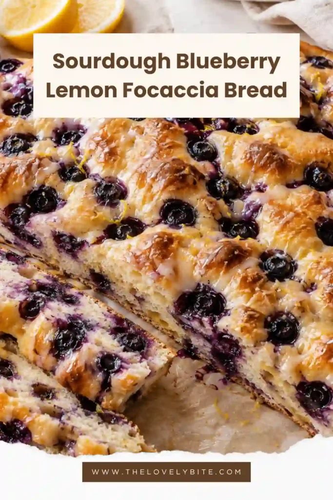 Lemon blueberry focaccia made with naturally fermented sourdough, fresh berries, butter, and lemon zest. The sliced bread reveals a light, airy interior beneath the golden glazed surface.