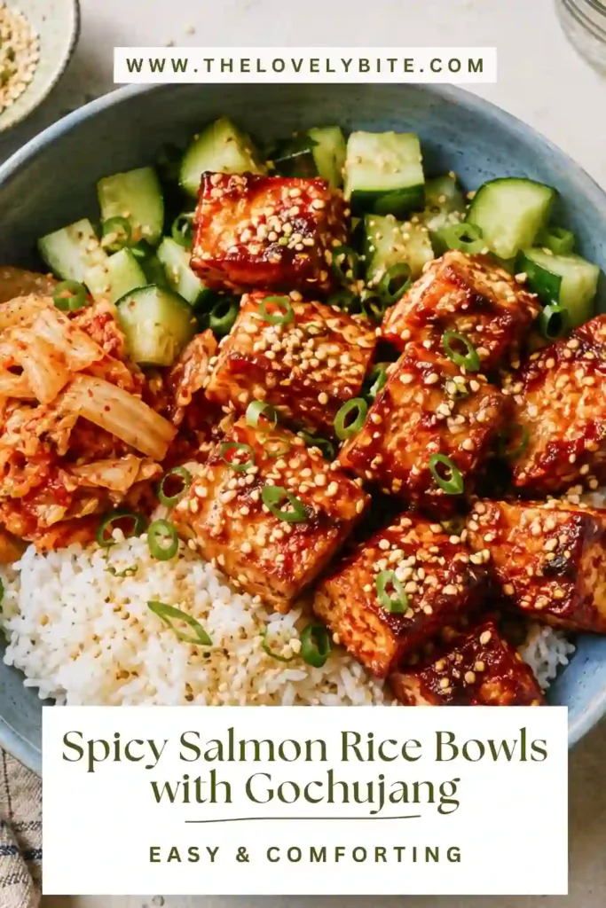 Spicy Salmon Rice Bowls topped with gochujang-glazed salmon bites, cucumber, kimchi, and toasted sesame seeds. Warm sticky rice creates the base for this colorful Korean-inspired meal.