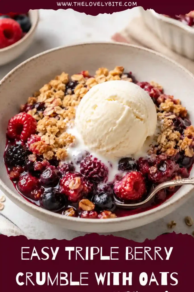 A serving of warm Triple Berry Crumble with juicy blueberries, raspberries, and blackberries beneath a buttery oat topping. The golden crumble is spooned into a bowl for a cozy homemade dessert.