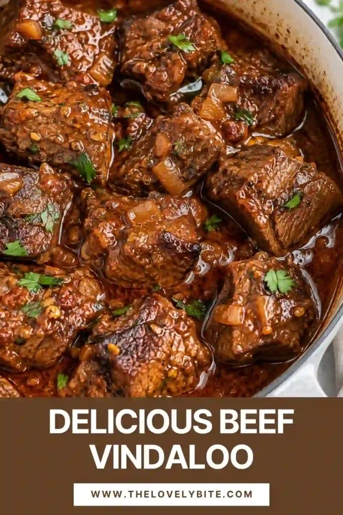 Close-up of spicy Beef Vindaloo with tender beef chunks and a thick, flavorful curry sauce. Basmati rice is served alongside the beef for soaking up the tangy, aromatic sauce.
