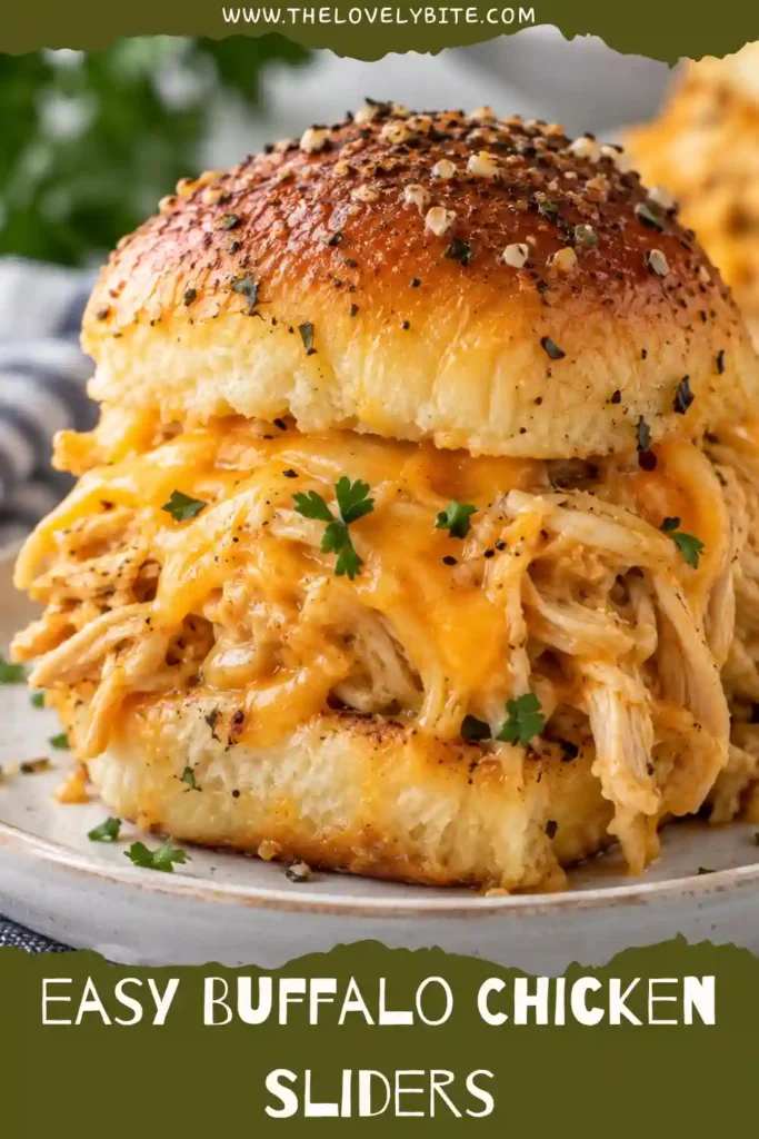 A close-up of cheesy Buffalo Chicken Sliders filled with spicy shredded chicken and creamy ranch dressing. Soft dinner rolls are topped with golden garlic butter and Italian seasoning.