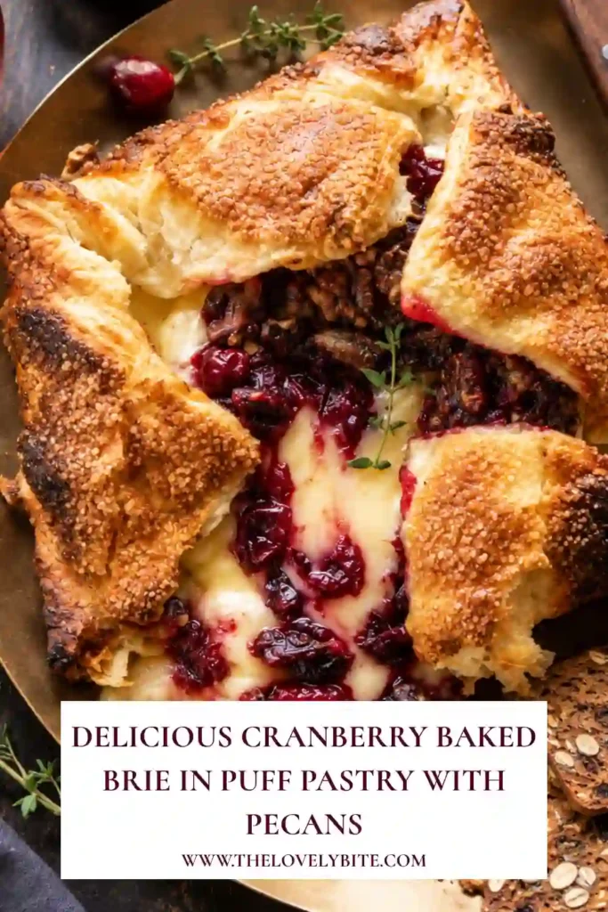 Cranberry Baked Brie served on a festive appetizer board with crackers, sliced apples, fresh cranberries, and rosemary. The golden puff pastry surrounds creamy Brie topped with homemade cranberry sauce and toasted pecans.