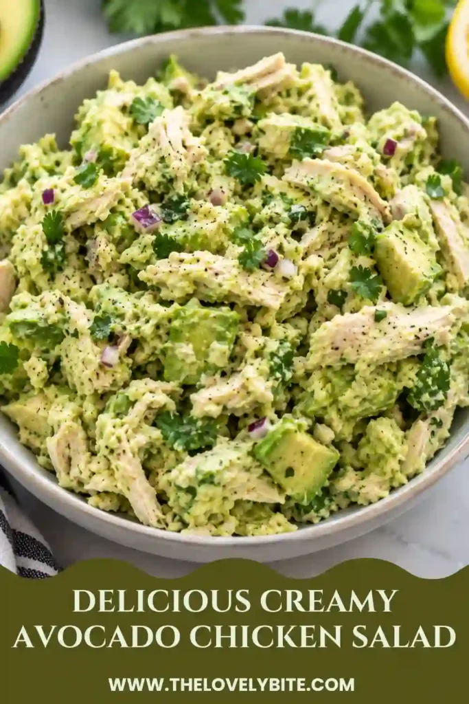 Close-up of creamy avocado chicken salad showing tender shredded chicken, ripe avocado pieces, and finely chopped vegetables. The rich avocado and mayonnaise dressing creates a smooth texture with fresh green herbs throughout.