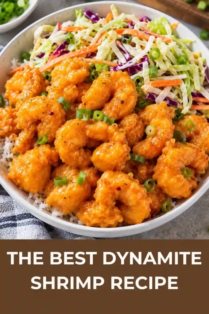 A bowl of crispy dynamite shrimp coated in a creamy, spicy orange sauce. Golden fried shrimp are arranged with fresh green onions for a flavorful restaurant-style appetizer.