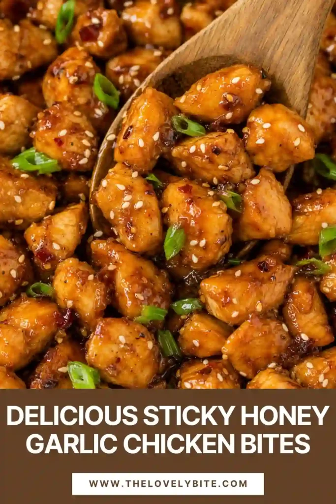 Skillet garlic chicken bites with a shiny honey glaze, toasted sesame seeds, and chopped green onions. The bite-sized pieces are golden brown and richly coated in sauce.