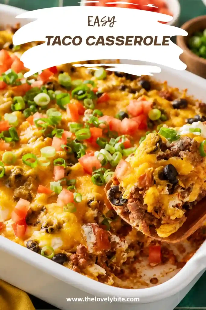 Cheesy ground beef taco casserole served warm from a baking dish with melted Cheddar and colorful taco toppings. Crushed tortilla chips create a flavorful base beneath the creamy beef and bean layers.