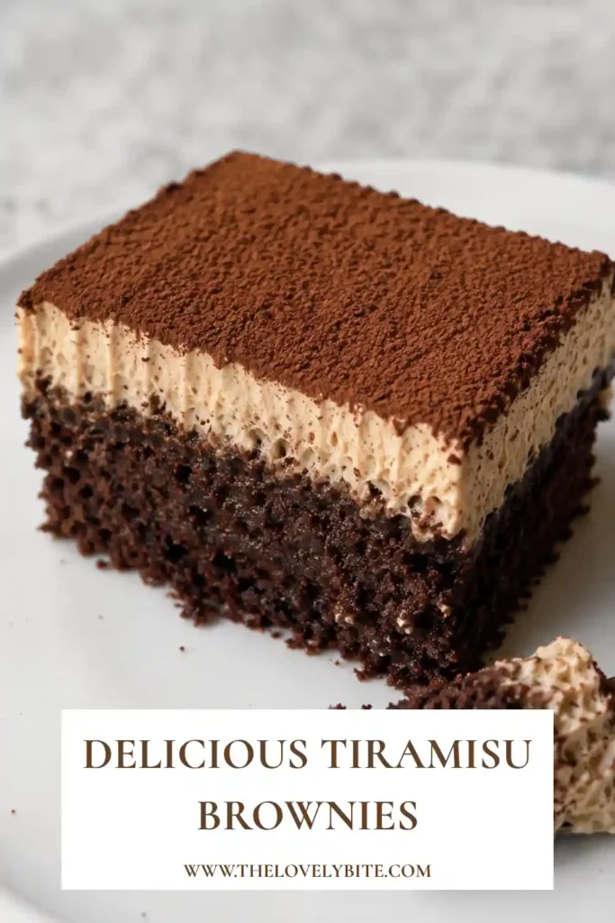 A close-up of chocolate tiramisu brownies topped with silky mascarpone cream. Cocoa powder is sprinkled over the creamy topping for a classic finish.