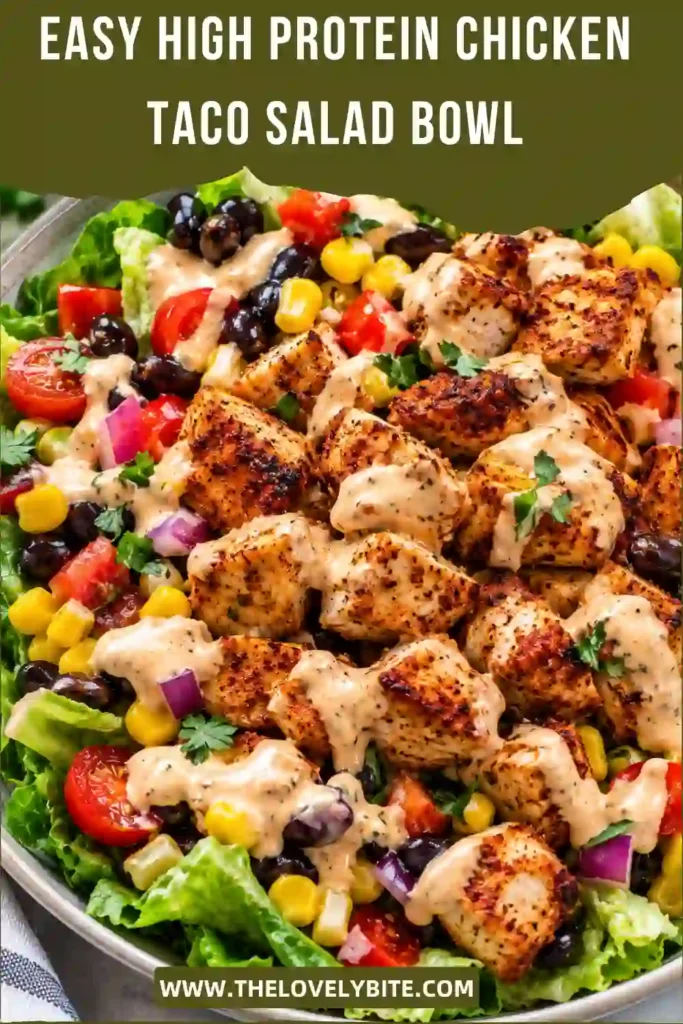 High protein taco bowl filled with seasoned chicken, romaine lettuce, black beans, sweet corn, tomatoes, red onion, and bell pepper. A creamy Greek yogurt taco dressing is drizzled over the top.